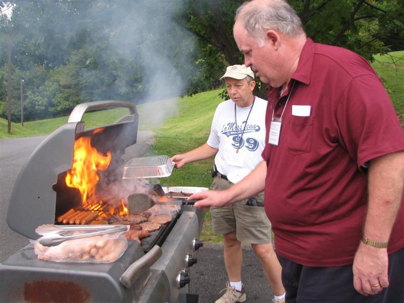 IMG_0346.JPG - The K-Family Weekend, a gathering of the Key Club and CKI leaders and Boards of Directors with the new Kiwanis Leadership Team begins with a Friday Cookout at the Front Royal Retreat.  A perfectly in control Chef Past Governor Charlie Adams is amazed he can stir up such a fire with those nice hot dogs and hamburgers.  Note the flames keep him hopping.  They were just right!  Concerned Fire Tender Bill Hand stands at the ready with a fire extinguisher ... a bottle of water.