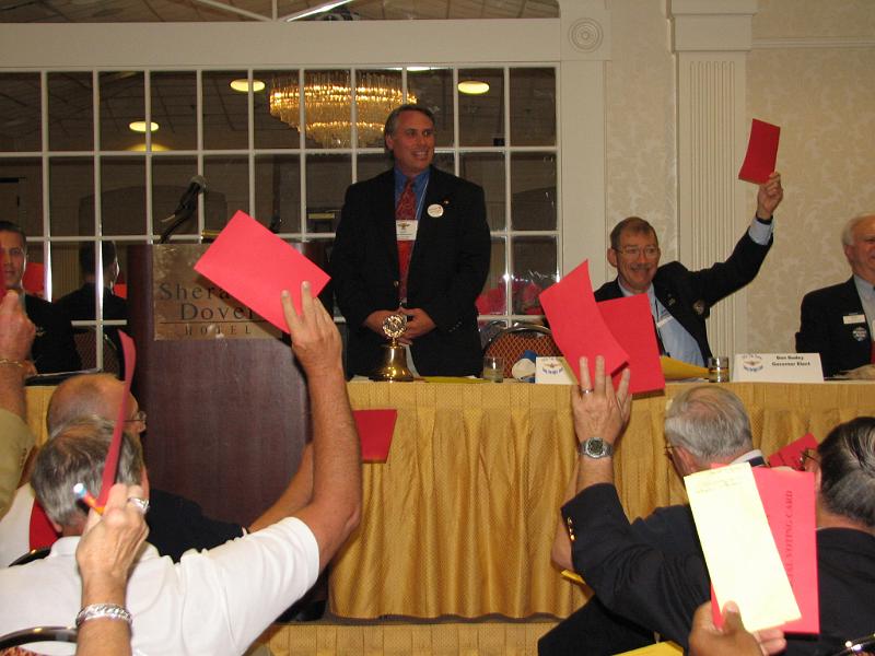 IMG_4470.JPG - Governor Tom Ganse presides over Delegate Session 1 on Saturday afternoon.  Delegates vote on an Amendment to the By Laws & Policies by showing the red cards, a visual reinforcement of the ‘Yeas and Nays’.  Works well … just like KI.